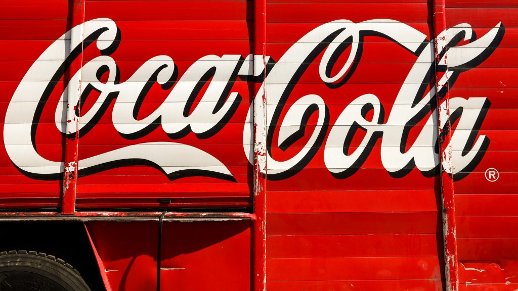 Coca Cola in white script on the side of a red truck