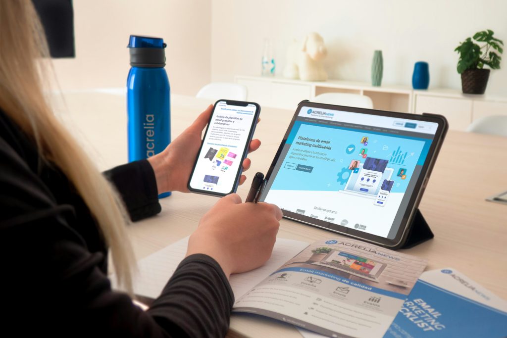 a person holding a phone while looking at a tablet on a desk a person holding a phone while looking at a tablet on a desk